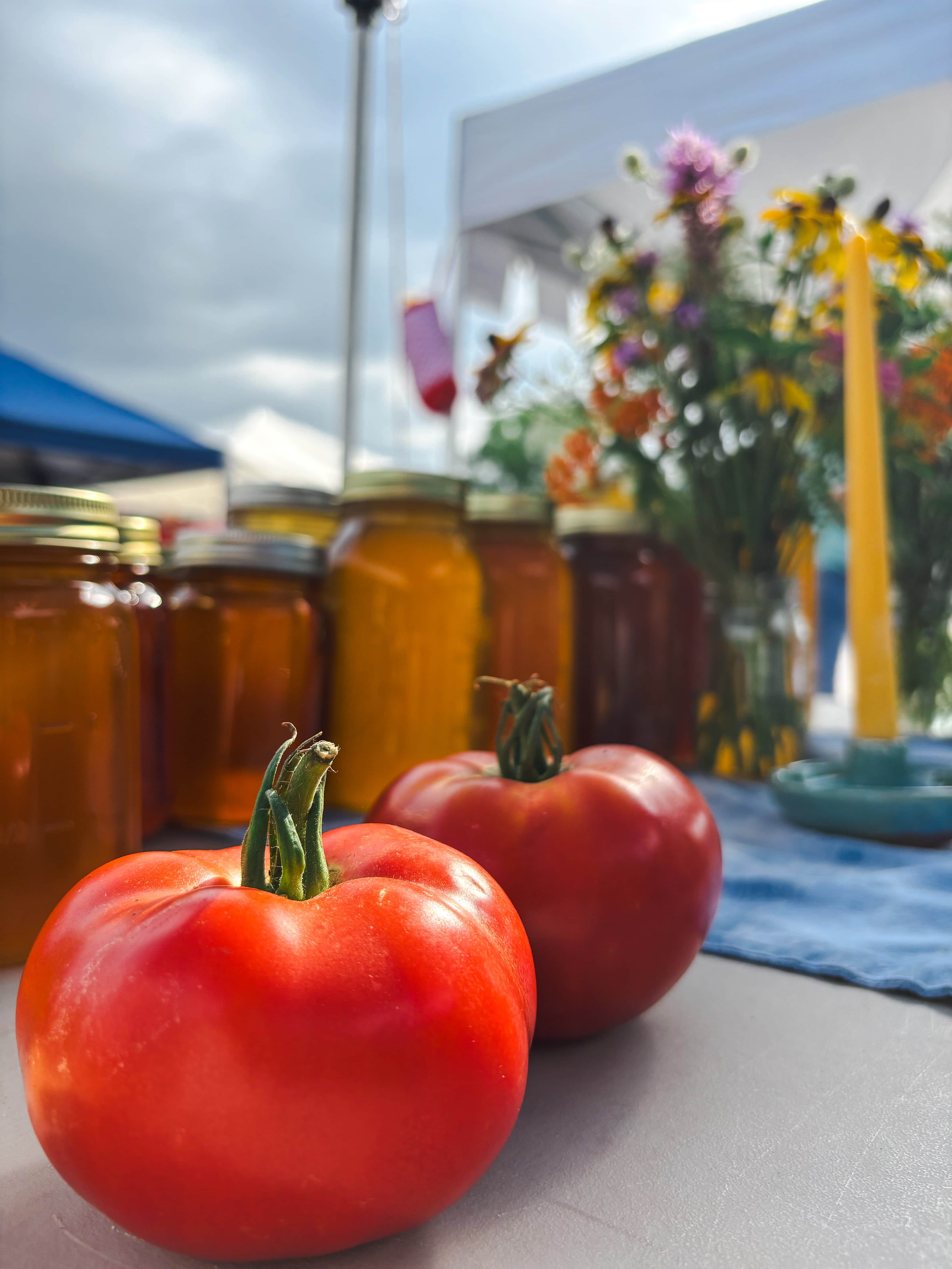 Tomatoes and jars on a market table.